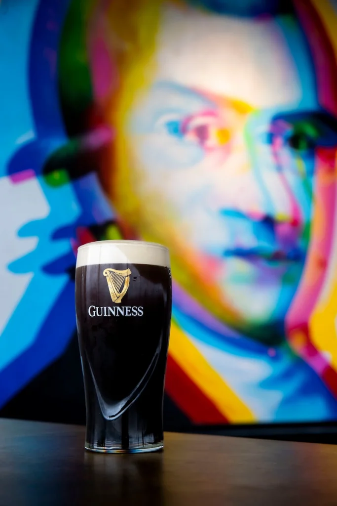 Guinness Pint in front of Colourful Portrait Mural