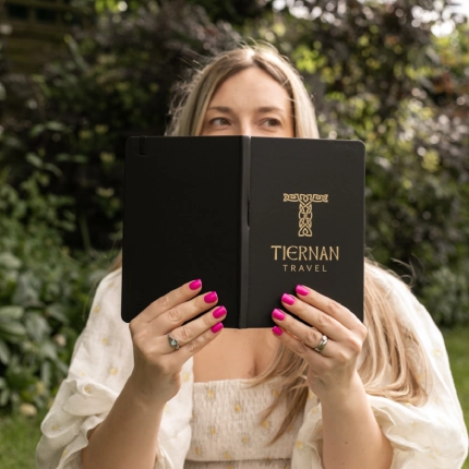 Person holding a black Tiernan Travel notebook outdoors