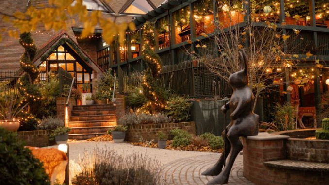 The enchanting courtyard entrance of the Rabbit Hotel and Retreat in County Antrim at dusk, with fairy lights, lush planting and a bronze hare sculpture